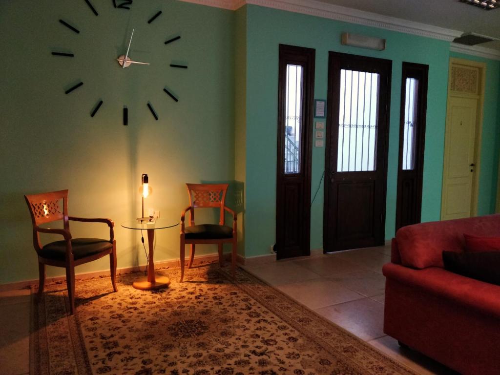 a living room with a clock on the wall and chairs at Hostel Roks in Haifa