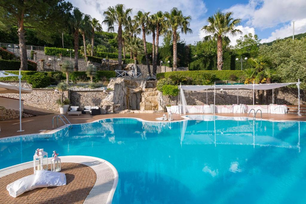 een groot blauw zwembad met palmbomen op de achtergrond bij Villa Al Rifugio in Cava deʼ Tirreni