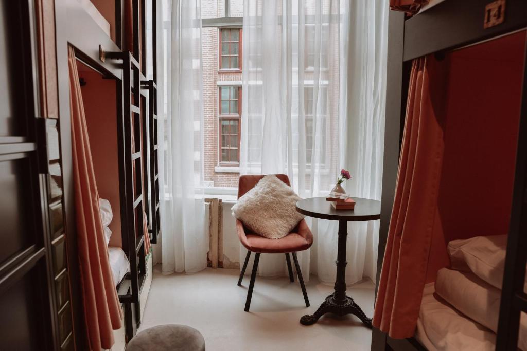 einen Stuhl und einen Tisch in einem Zimmer mit Fenster in der Unterkunft Durty Nelly&#39;s Inn in Amsterdam