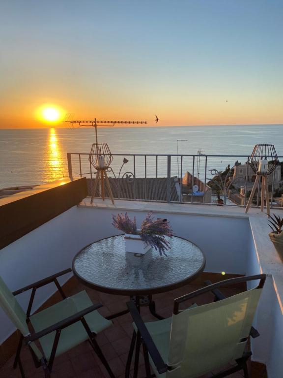 una mesa y sillas en un balcón con vistas a la puesta de sol en Affaccio su Stromboli, en Tropea