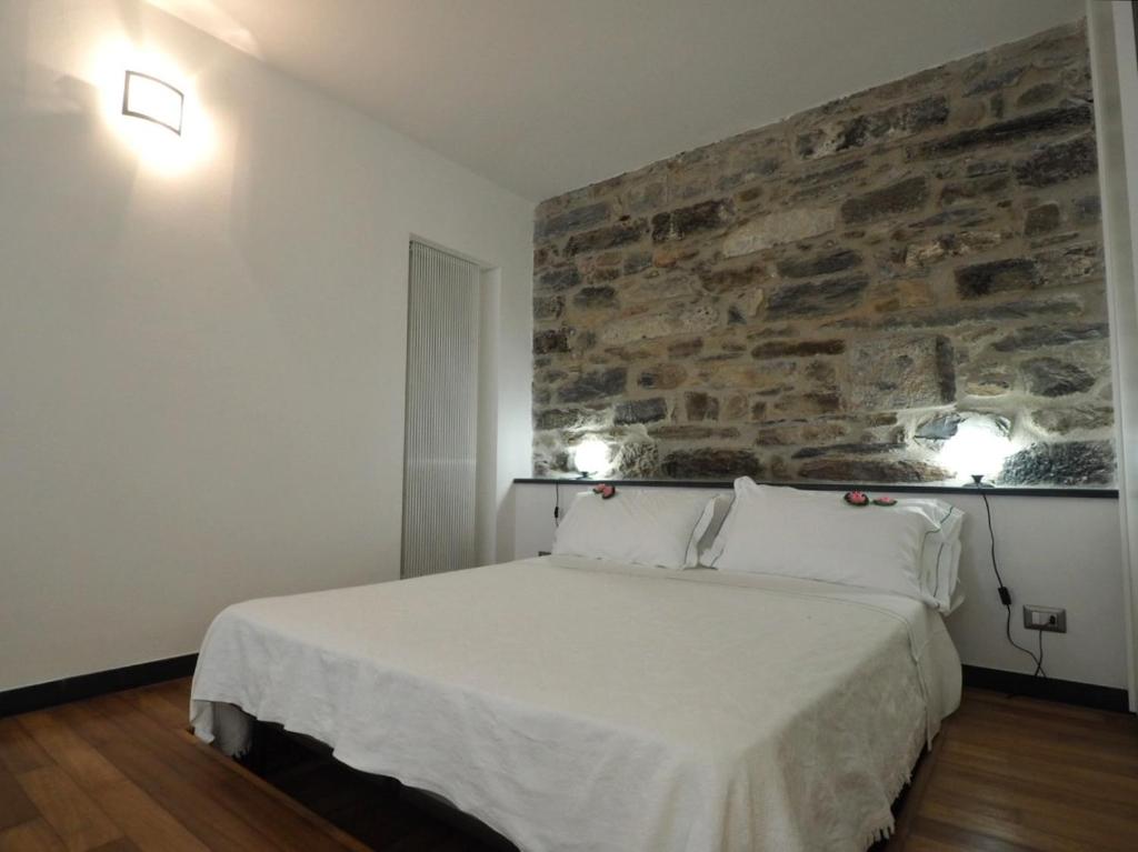 a bedroom with a white bed with a stone wall at appartamento da detta in Vernazza