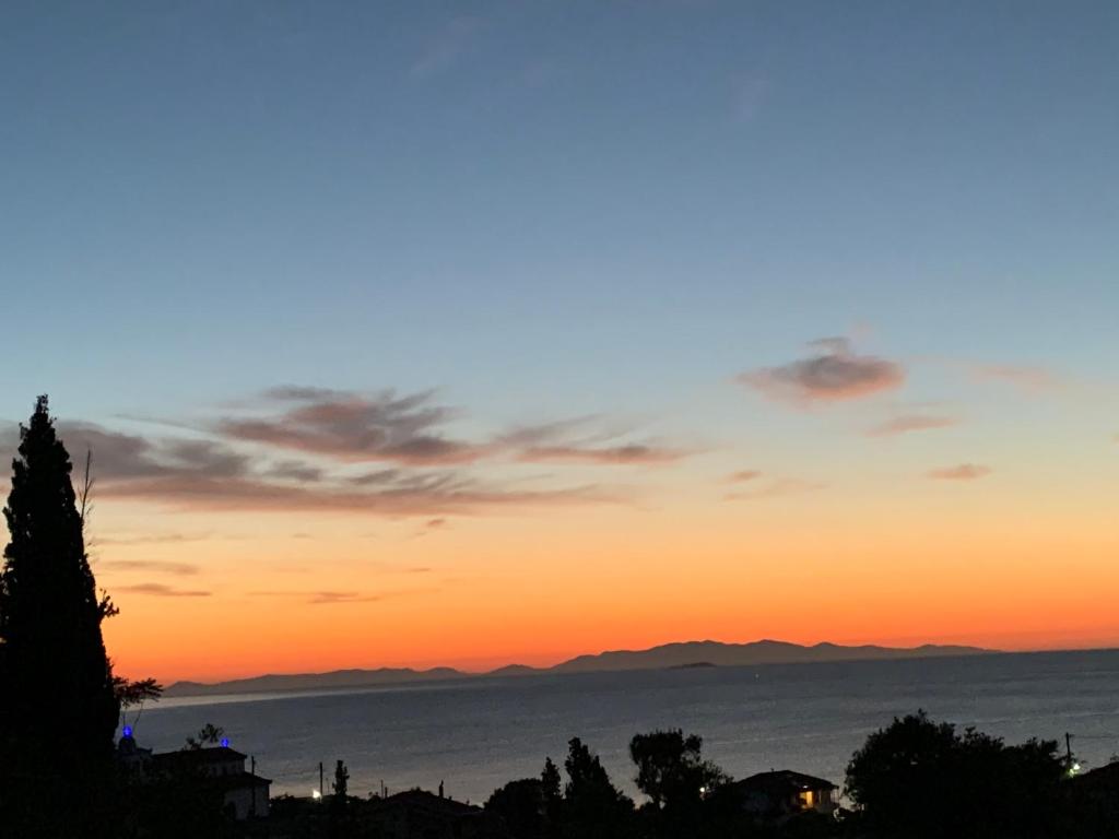 una puesta de sol sobre el océano con montañas en el fondo en Villa Riverside, en Platána