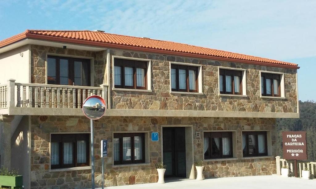 - un bâtiment en pierre avec un balcon au-dessus dans l'établissement Fragas da Canteira Hotel Rural, à Lires