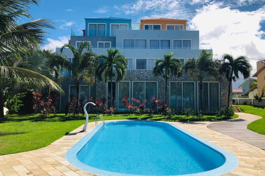 uma casa com piscina em frente a uma casa em Apart Hotel Praia dos Carneiros Apto 101 em Praia dos Carneiros