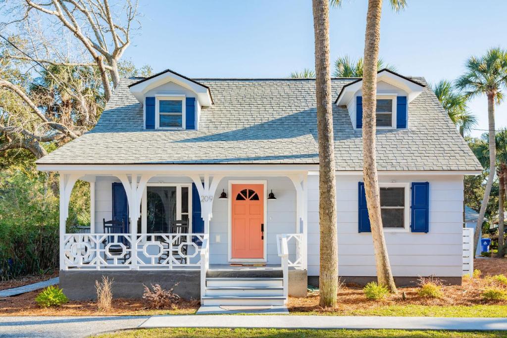 a white house with a red door and palm trees at Folly Vacation Beautiful Beach Cottage 209-A in Folly Beach