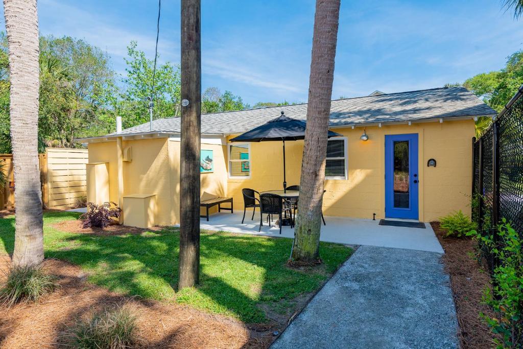 a yellow house with a table and chairs in a yard at Folly Vacation Laid Back Casual Beach Bungalow 209-B in Folly Beach