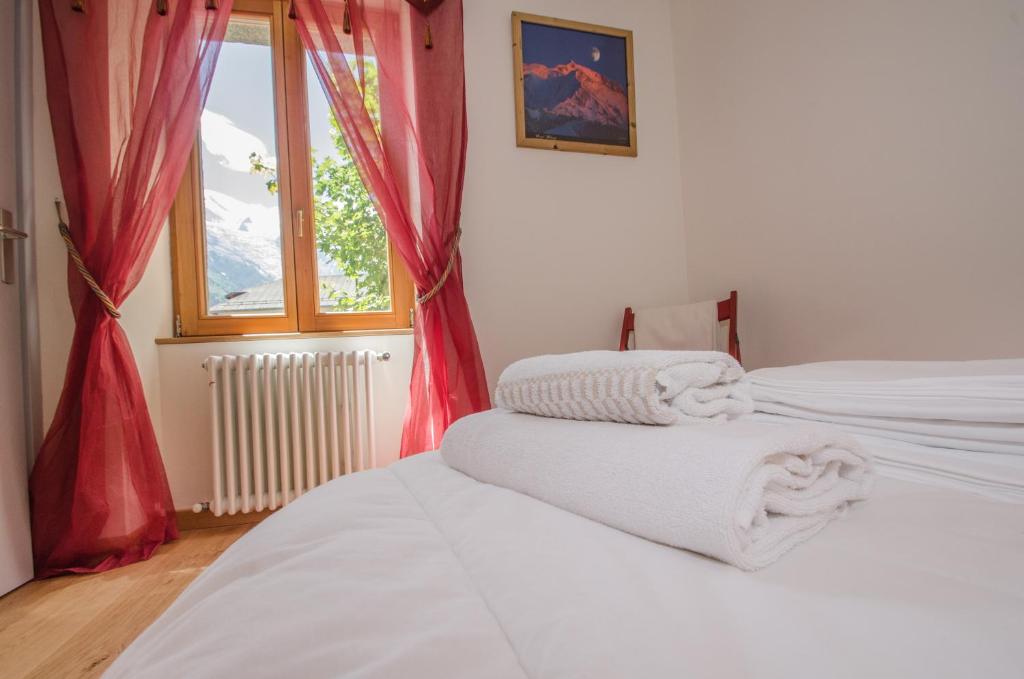 1 dormitorio con 2 camas, cortinas rojas y ventana en Campanela, en Chamonix-Mont-Blanc