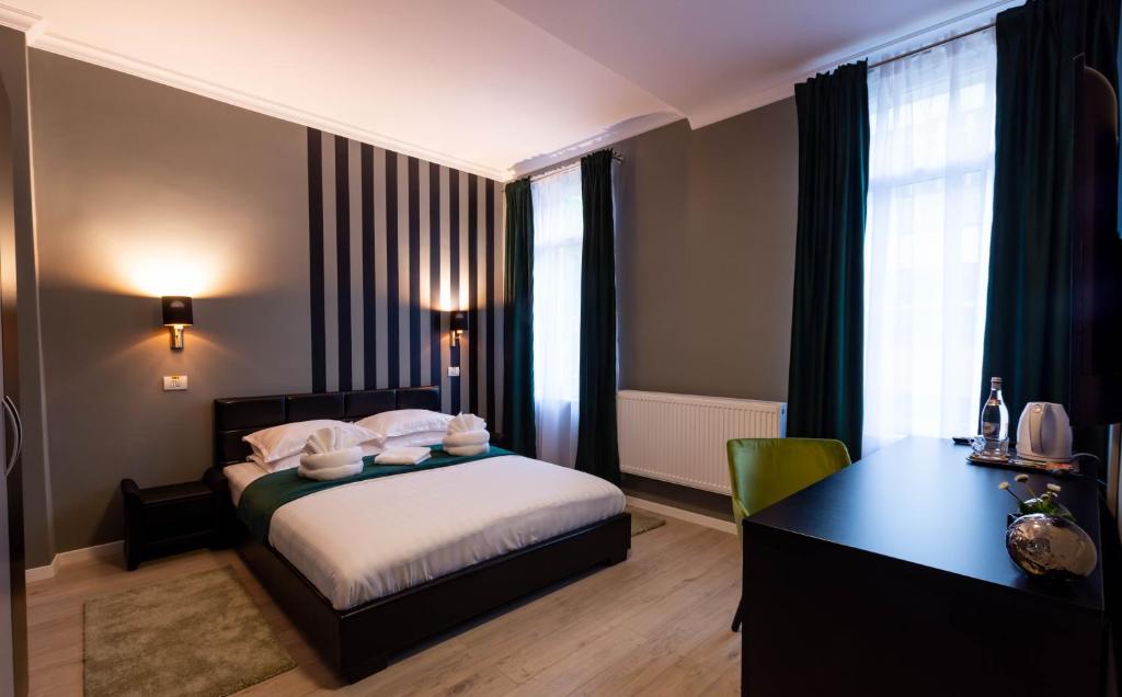 Cette chambre comprend un lit, un bureau et une fenêtre. dans l'établissement Resita Residence, à Reşiţa