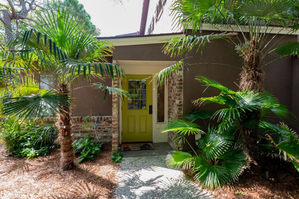 a yellow front door of a house with palm trees at Folly Vacation 620 apartment w/bonus room, one block to the beach & pet friendly in Folly Beach