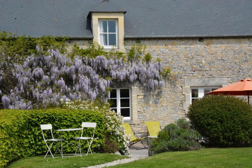 ein Haus mit zwei Stühlen und einem Busch mit lila Blumen in der Unterkunft Les Chaufourniers/L'Etable in Crouay