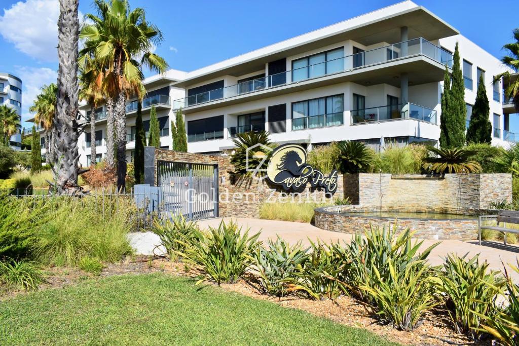 un grande edificio bianco con palme di fronte di Cavalo Preto Luxury Beach Apartment by Golden Zenith a Quarteira