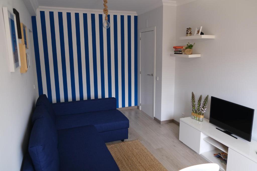 a living room with a blue couch and a television at Atlantic Getaway - T1 100 m to the Waves in Buarcos