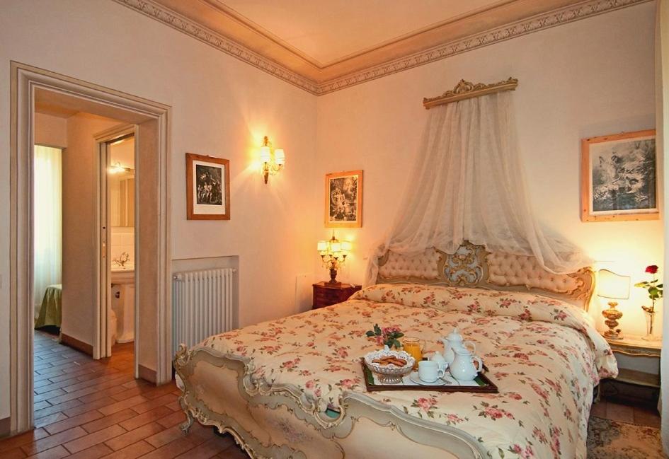 - une chambre avec un grand lit à baldaquin dans l'établissement Villa Lombardi, à Camaiore