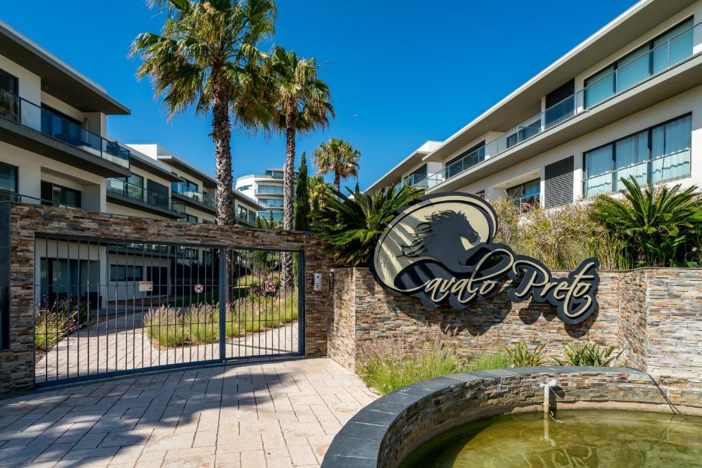 een poort bij de ingang van een hotel met een bord bij BmyGuest - Cavalo Preto Beach Apartment in Loulé