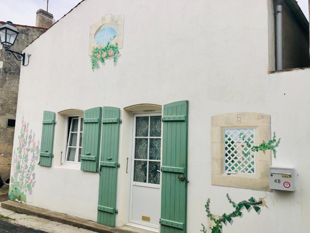 a white building with green shutters and a window at Petite maison tout confort in Esnandes