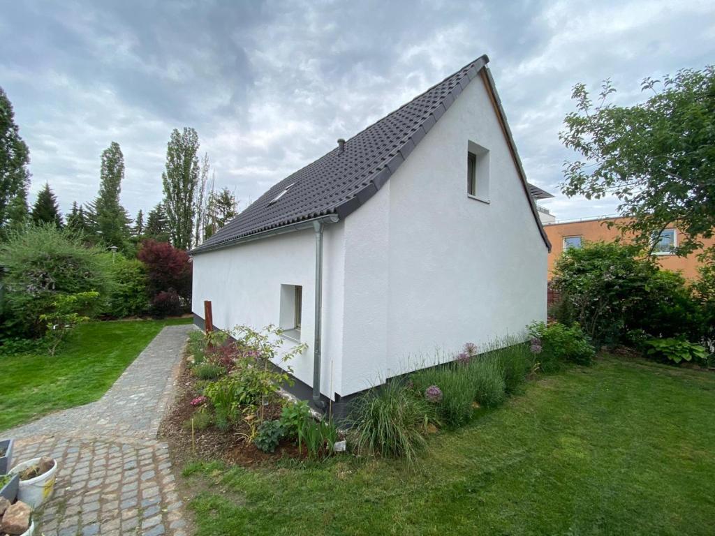 una casa bianca con un tetto nero in un cortile di dresden-ferien haus a Dresda