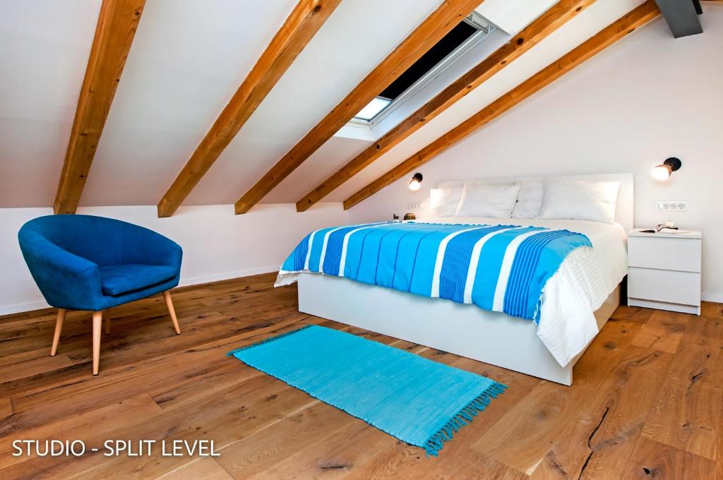 sypialnia z łóżkiem i niebieskim krzesłem w obiekcie Porta Azzurra Apartments w Rovinj