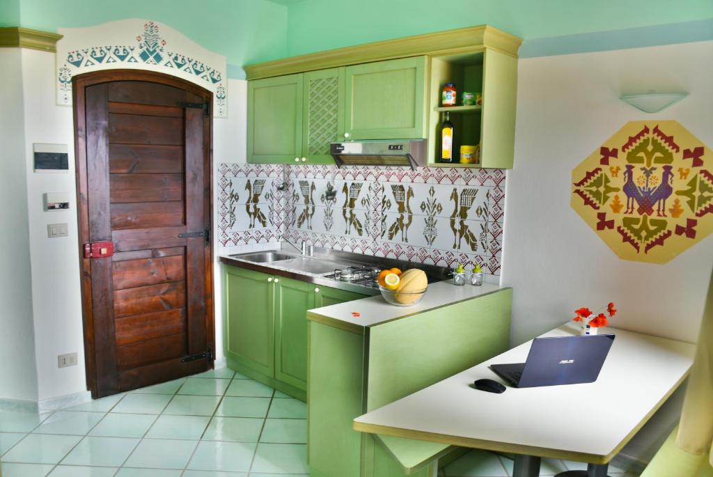 una cucina con armadi verdi e un computer portatile su un bancone di Casa Mare Cala Rossa a Trinità dʼAgultu