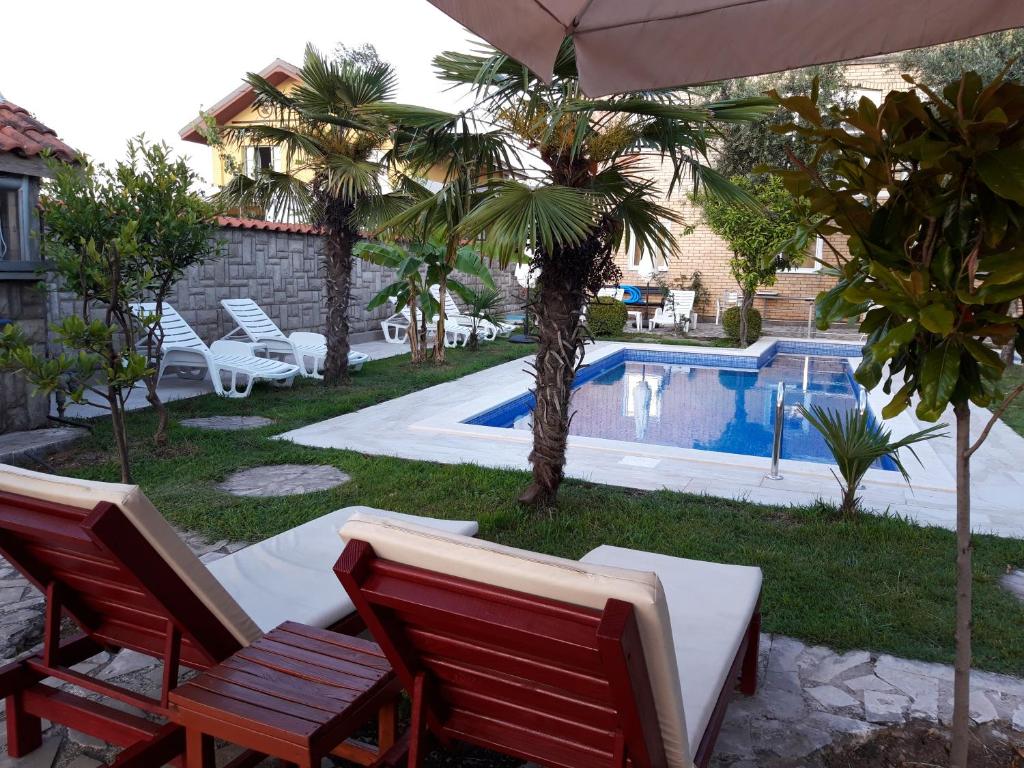 een tuin met 2 stoelen en een zwembad bij Kazablanka Rooms Aerodrom in Podgorica