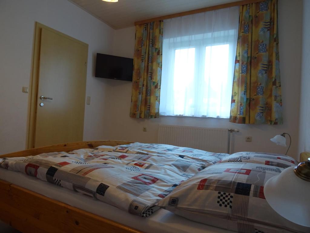 a bed with a comforter and a window in a bedroom at Bauernhof Familie Tauber-Scheidl in Grossmeinharts