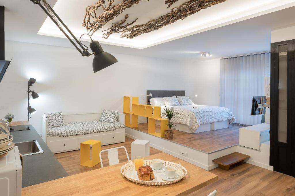 a bedroom with a bed and a living room at Suite Nest in Padrón