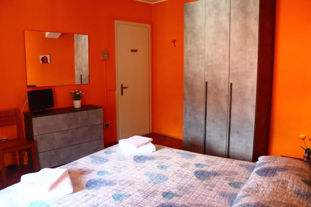 a bedroom with orange walls and a bed and a cabinet at Albergo Del Lago in Bellano