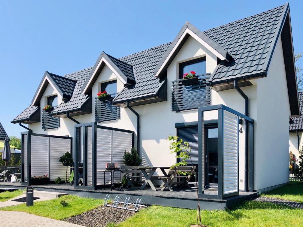 a white house with black roof at Domki Apartamenty Akacja in Sianozety