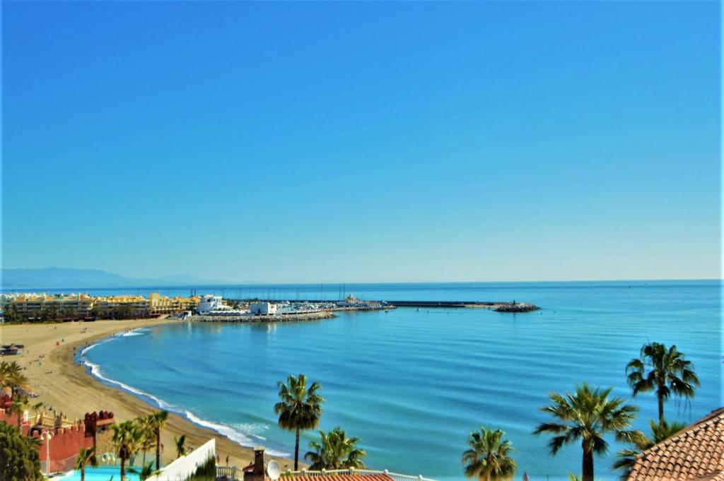 a view of a beach with palm trees and a pier at Excepcional Duplex al lado de la playa y con vistas al mar in Benalmádena