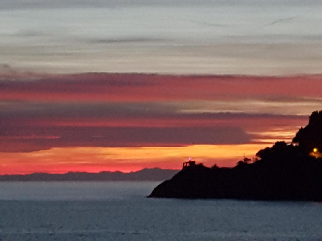 a sunset over the ocean with a mountain in the distance at Albergo Lungomare in Bonassola