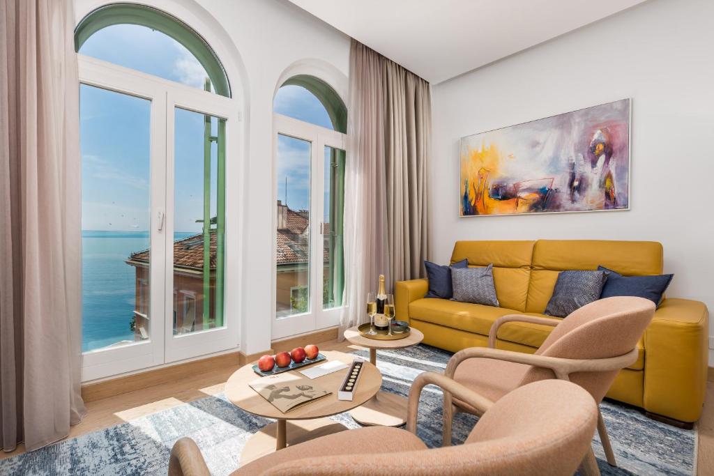 ein Wohnzimmer mit einem gelben Sofa und Fenstern in der Unterkunft OLA Opatija Luxury Apartments in Opatija