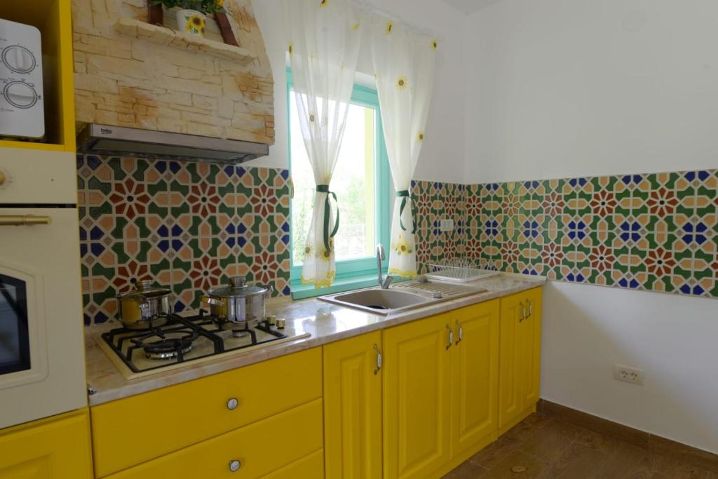 uma cozinha com armários amarelos, um lavatório e uma janela em Pensiunea HAPPY em Schitu-Topolniţei