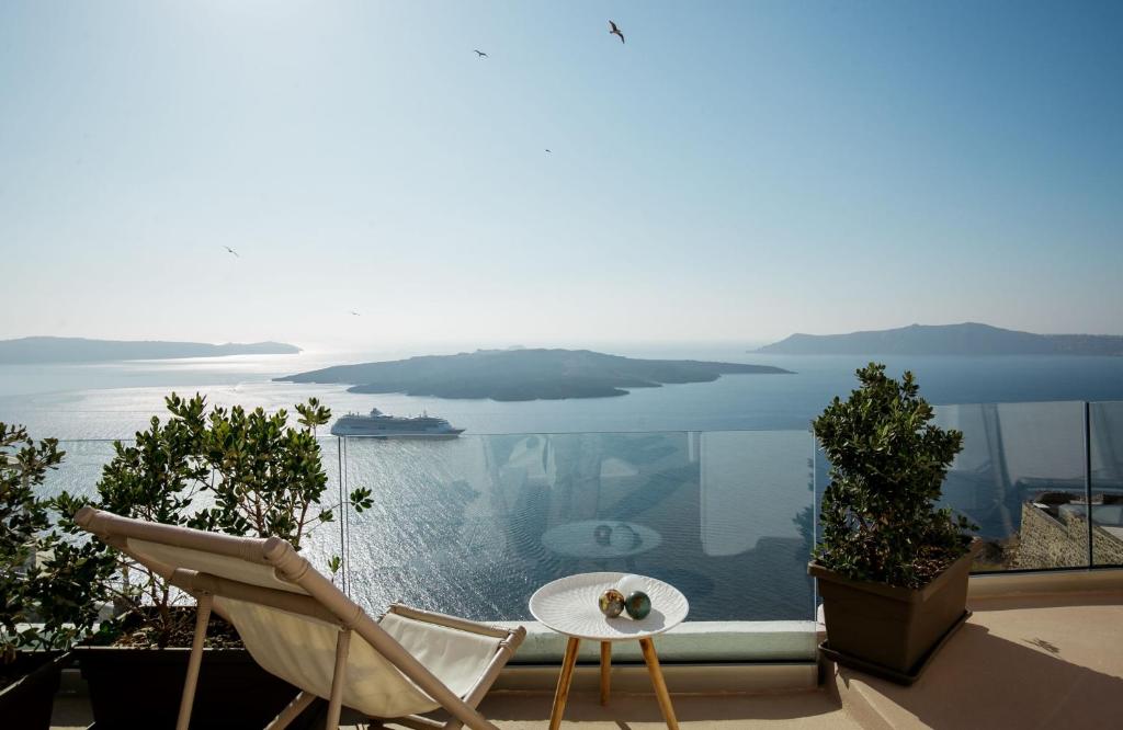 a balcony with a table and chairs and a view of the water at The Globe Suites Villa in Fira
