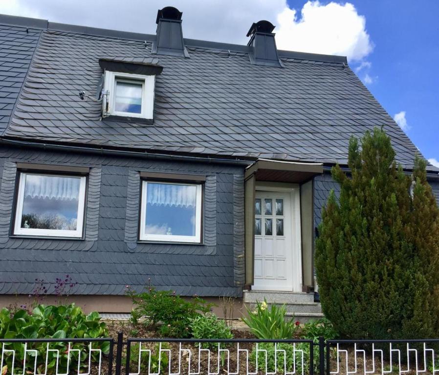 a house with a black roof and a white door at Ferienhaus am Rennsteig in Schmiedefeld am Rennsteig