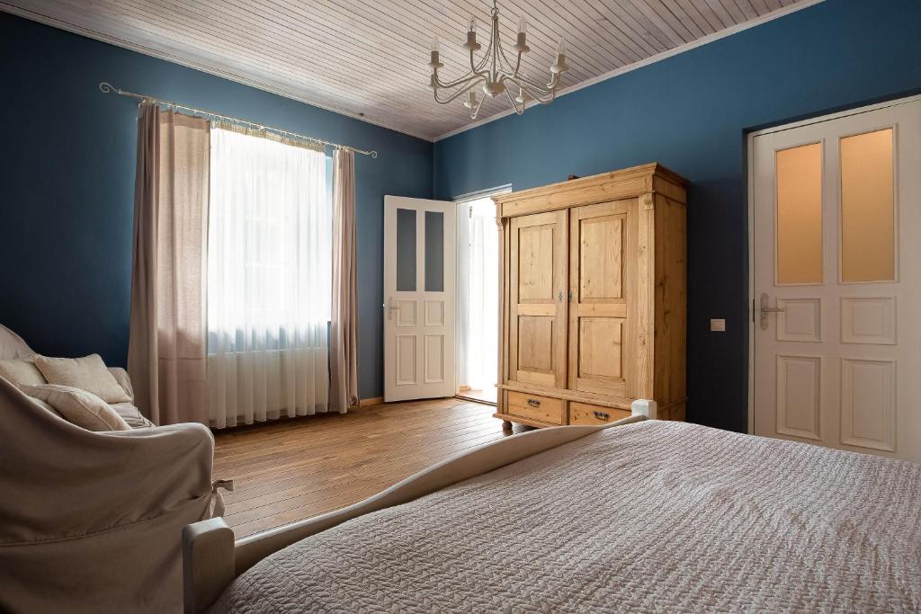 a bedroom with blue walls and a bed and a chair at Karlamuiza Country Hotel in Kārļi