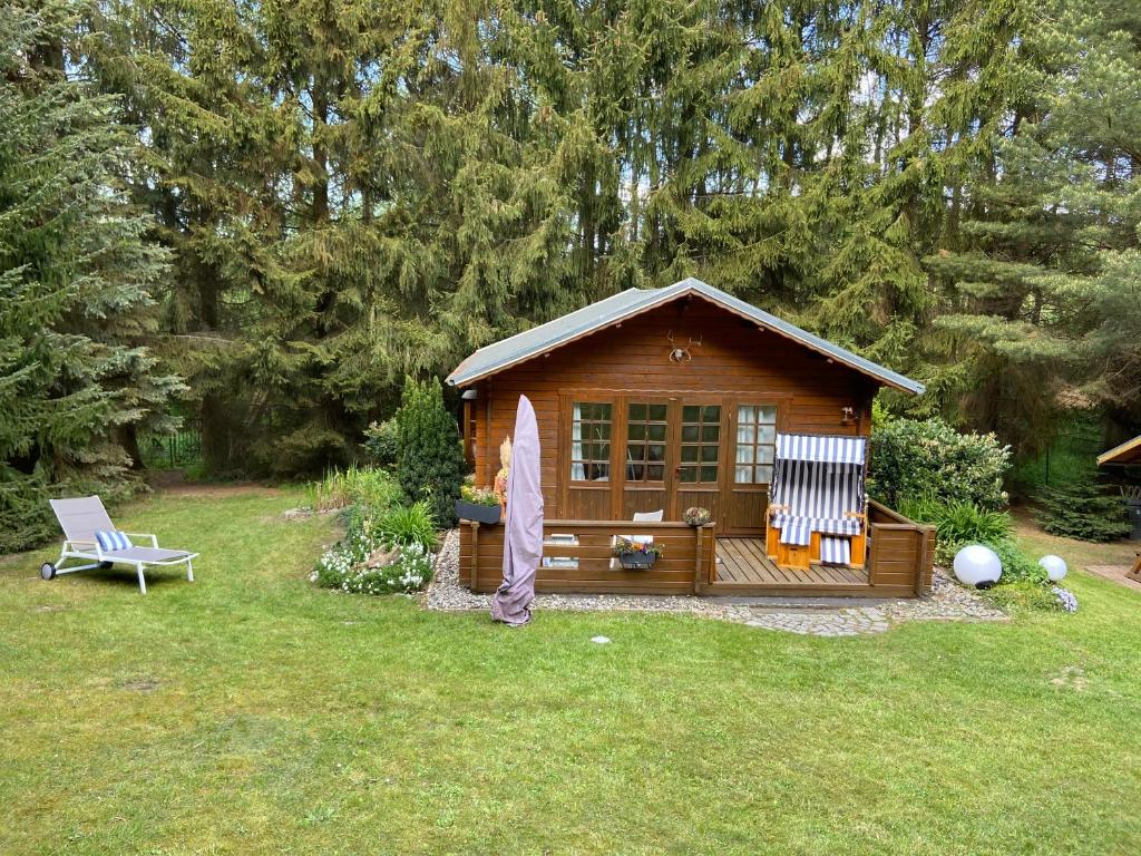 a small cabin in a yard with a chair at Blockhütte in Rostock Land in Papendorf