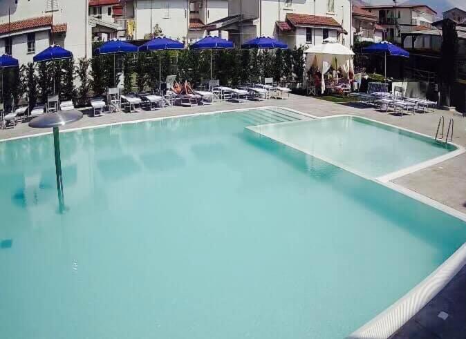 an empty swimming pool with blue umbrellas and chairs at Apparthotel Residence Riviera dei Cedri in Santa Maria del Cedro