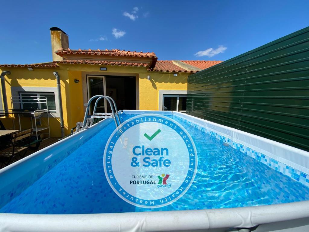 una piscina con un cartel limpio y seguro junto a una casa en Azeitão Duplex with pool 25 min from Lisbon, en Azeitão