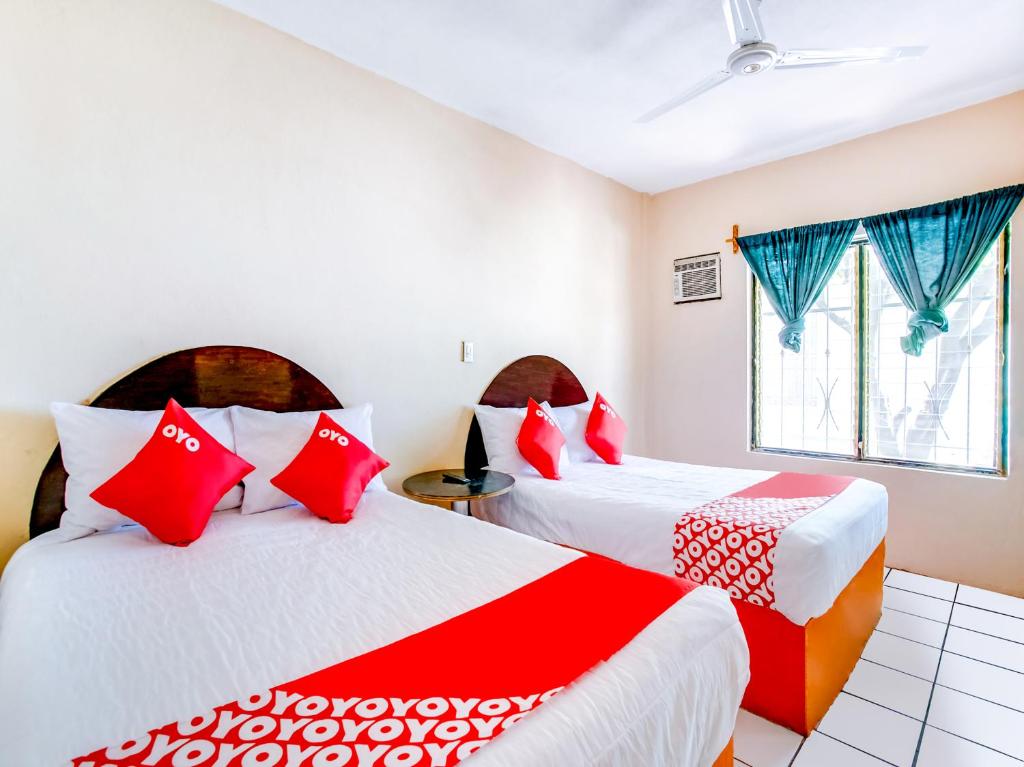 two beds in a room with red and white pillows at OYO Hotel Margarita in Tlaquiltenango