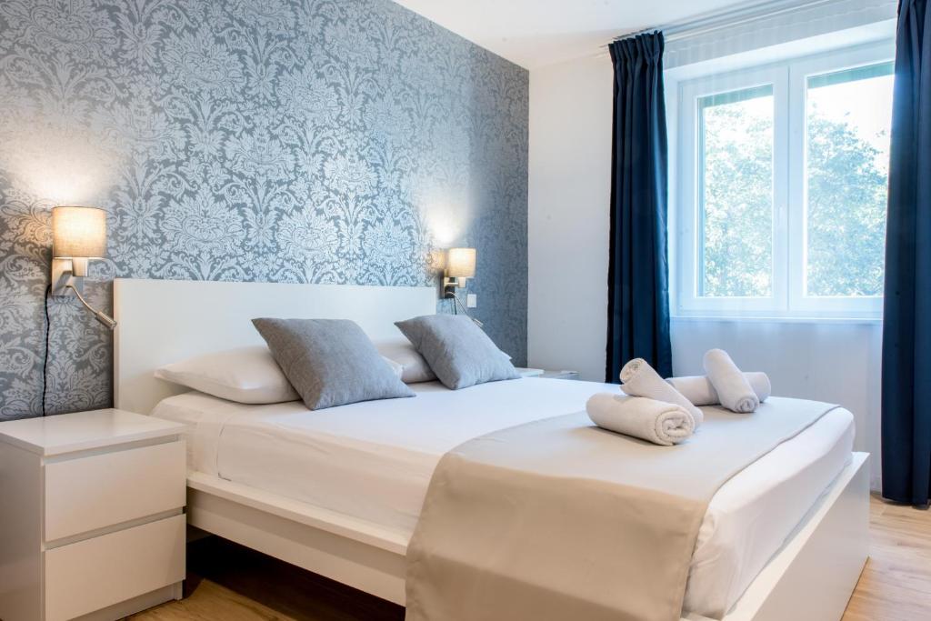 two beds in a bedroom with blue wallpaper at Wind Rose Split in Split