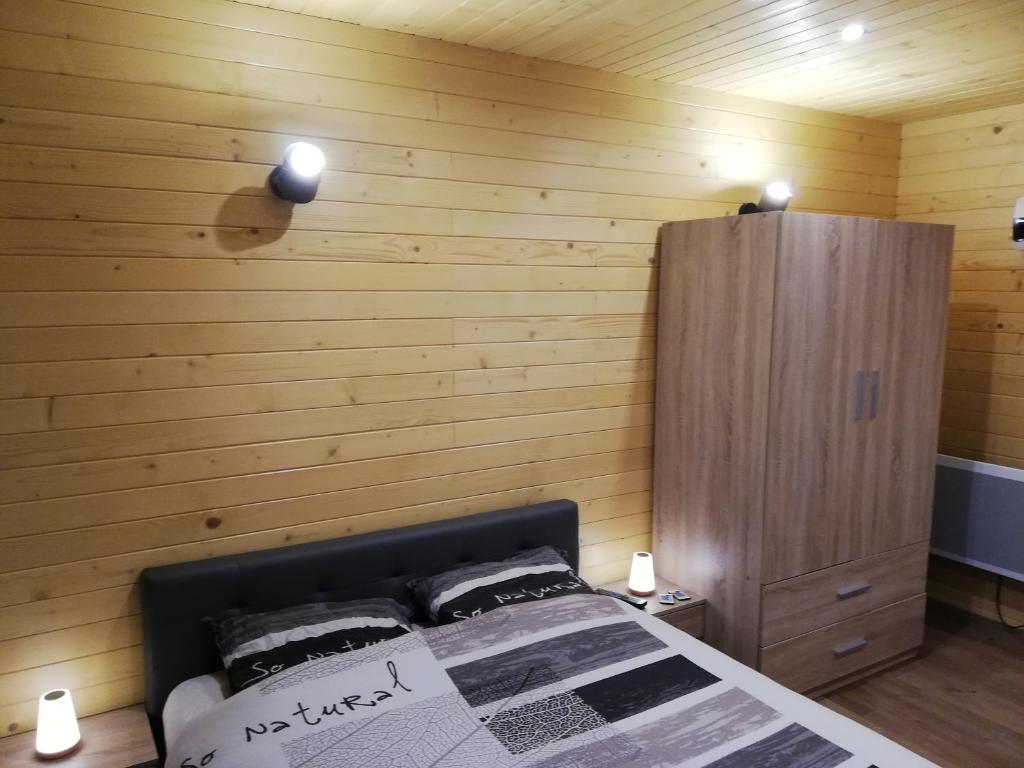 a bedroom with a bed and a wooden wall at Lodge du Léman in Sciez