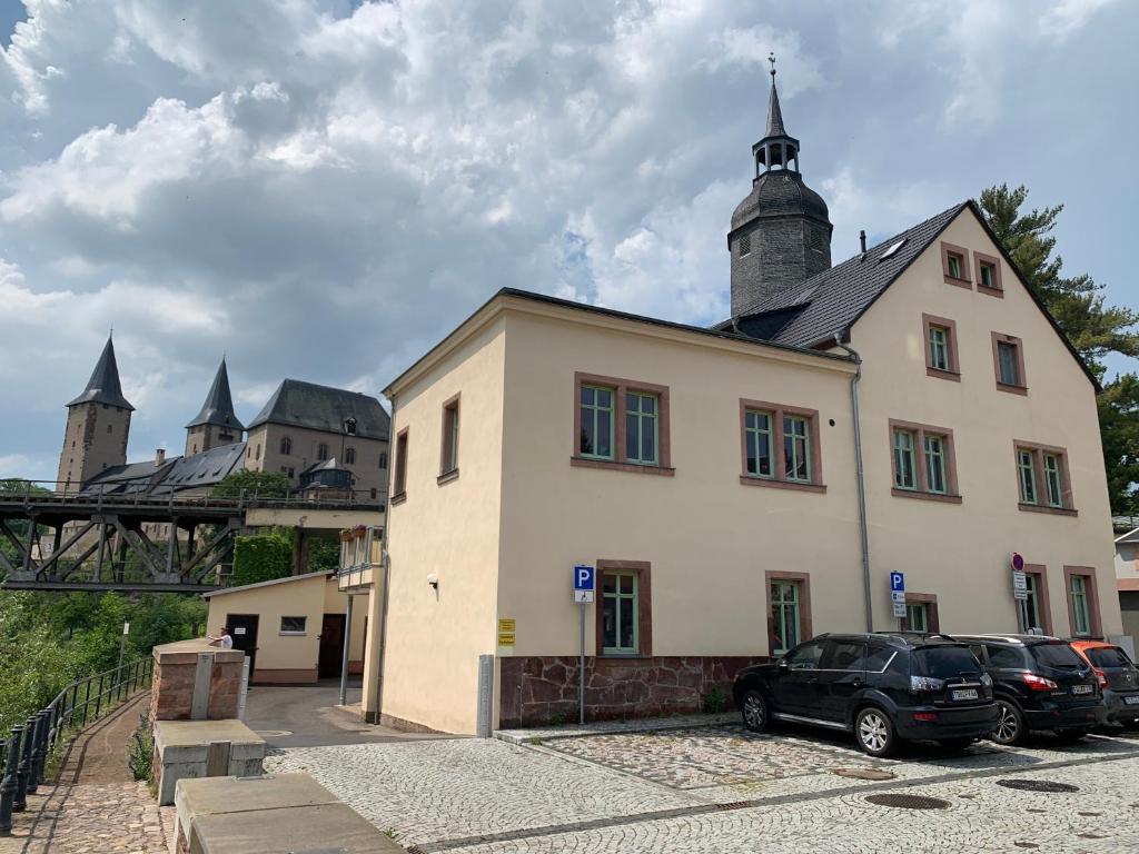 ein Gebäude mit Autos auf einem Parkplatz in der Unterkunft Ferienwohnung am Schloss Rochlitz in Rochlitz