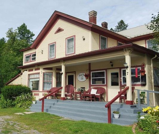 a house with a porch with a table and chairs at brookside motor inn in Upper Jay