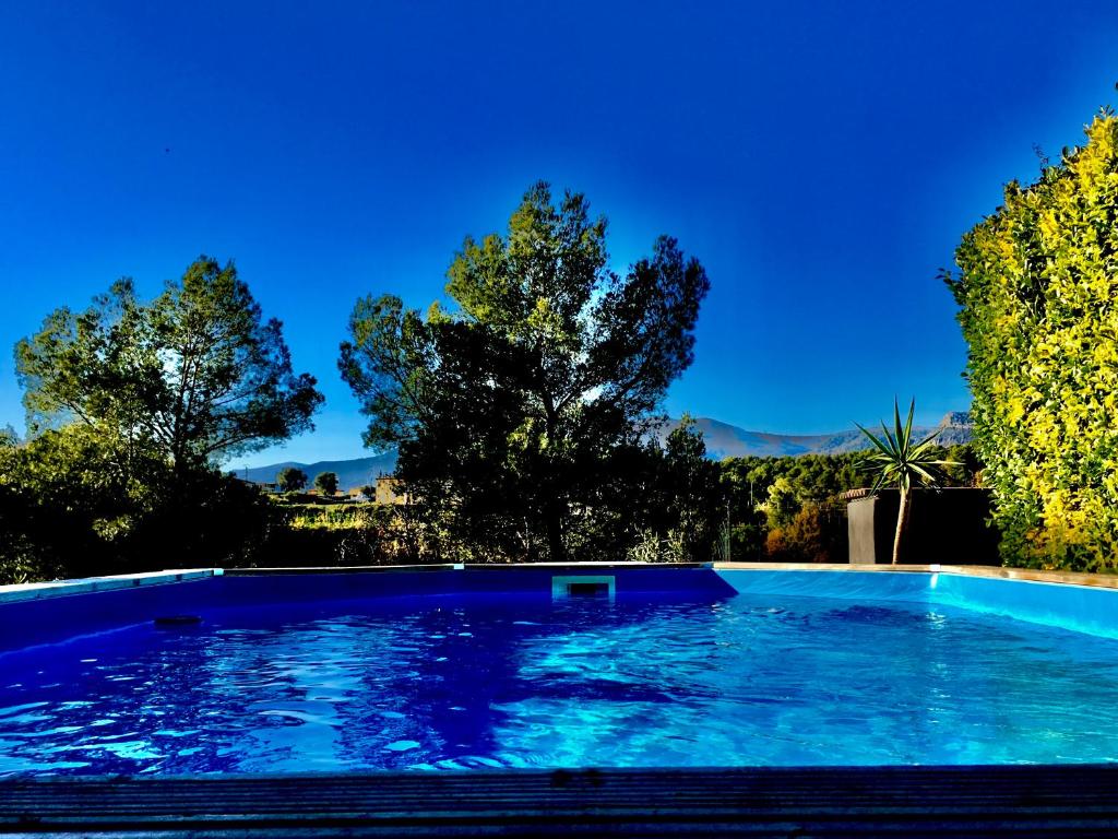 uma piscina azul com árvores ao fundo em La Gaude, villa 6 personnes-jardin-piscine-vue dégagée au calme em La Gaude