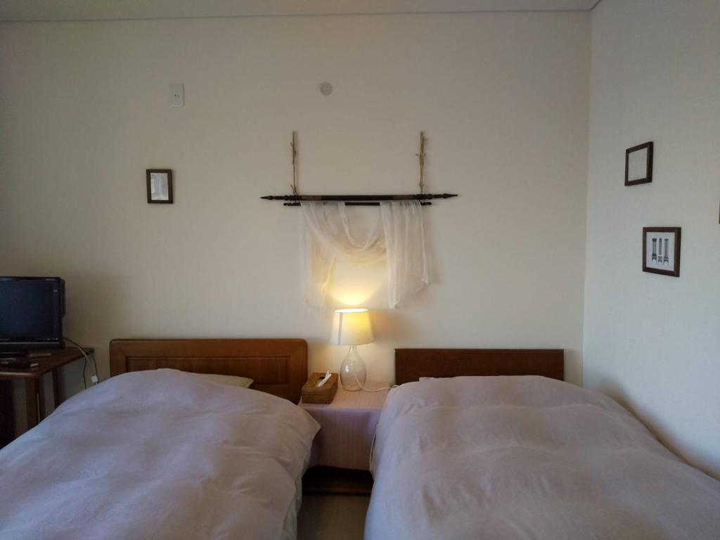 - une chambre avec deux lits et une lampe sur une table dans l'établissement KEI, à Lac Tōya