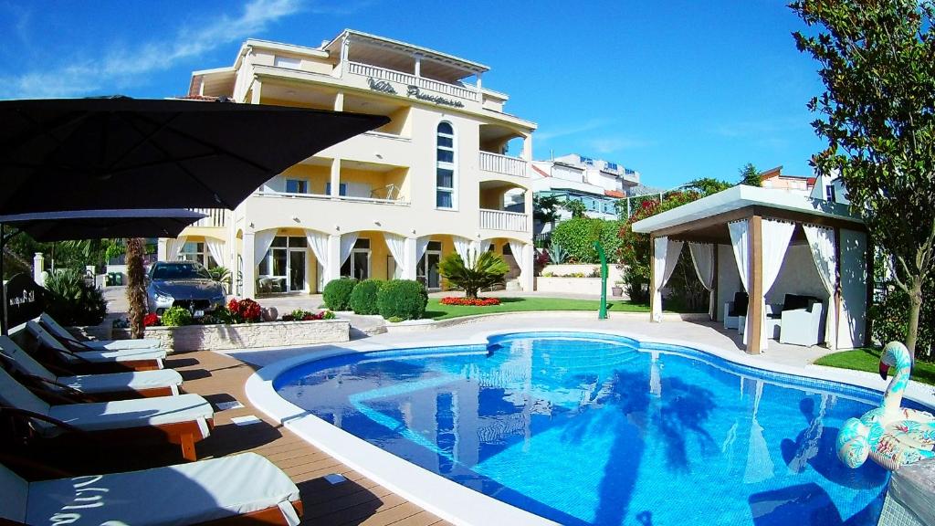 a swimming pool in front of a large house at Villa Principessa Podstrana in Podstrana