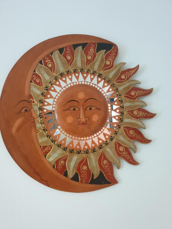 a wooden wall clock with a face in a sunburst at A 7 KM DA SALO' CASA DEL SOLE MANSARDA in Gavardo