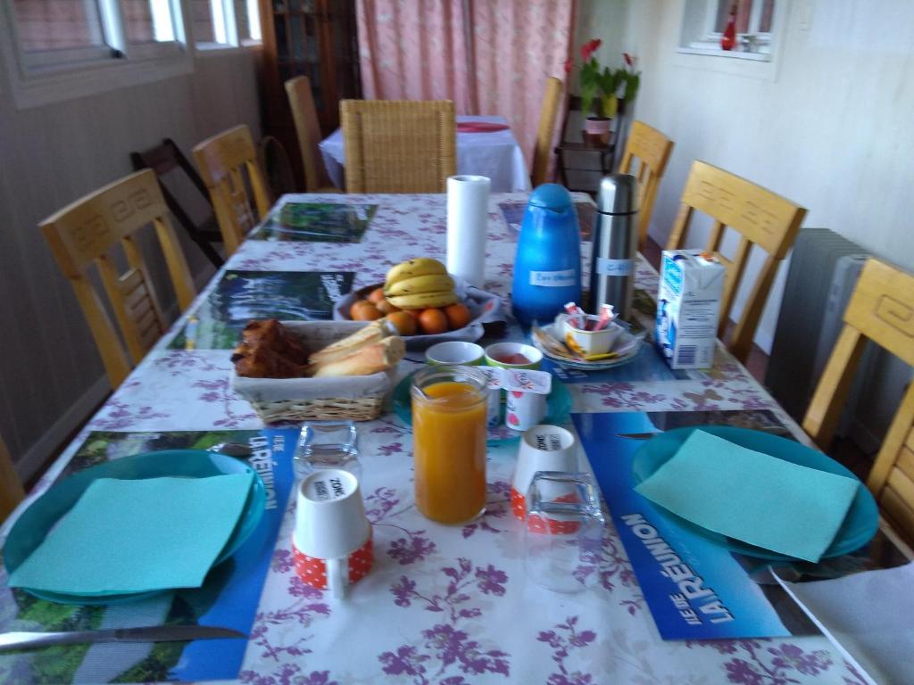a dining room table with a breakfast of juice and fruit at Au fruit delicieux in La Plaine des Cafres
