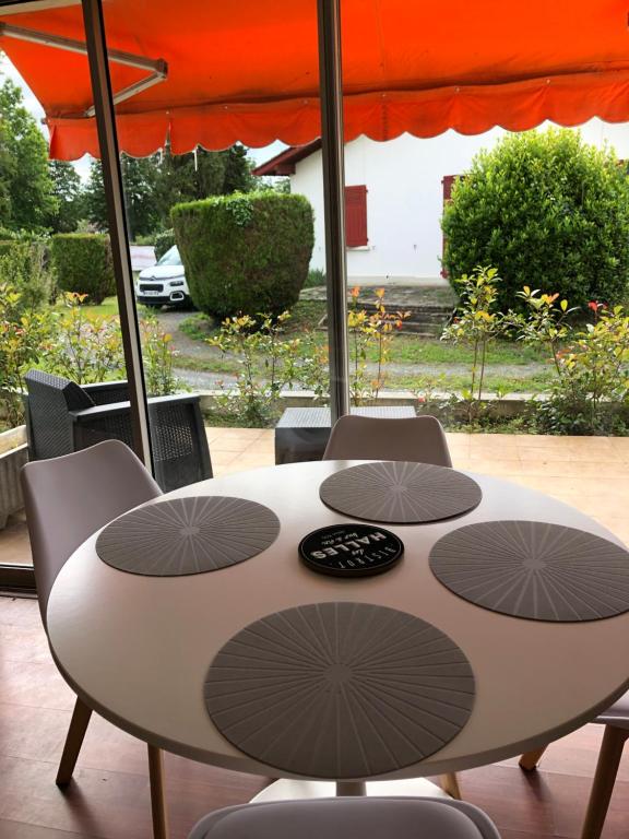 ein Tisch mit Stühlen und einem Sonnenschirm auf einer Terrasse in der Unterkunft Appartement cosy, en rez de chaussée, en plein centre de CAmbo les Bains in Cambo-les-Bains