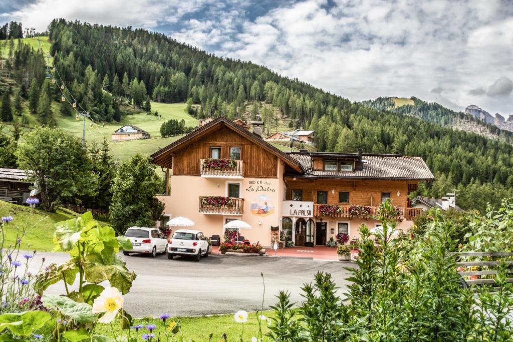 ein Gebäude in den Bergen mit Autos vor dem Haus in der Unterkunft B&B Apartments La Palsa in St. Kassian