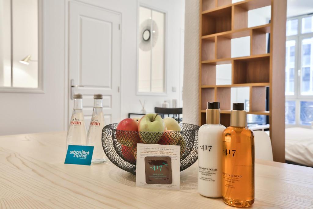 - une table avec des bouteilles et un bol de pommes dans l'établissement 34 - Urban Luxury Paris Louvre, à Paris